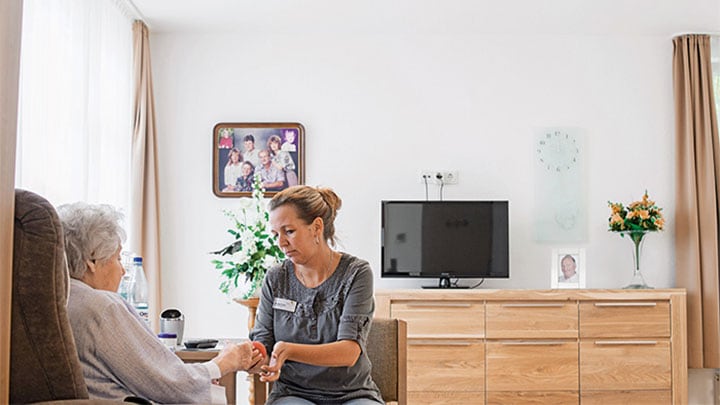 A staff taking care of a patient at Elderly Care Home under dynamic lighting by Philips Healtcare Lighting solutions