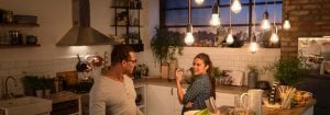 "Modern kitchen with vintage style LED pendant lights illuminating two women enjoying dinner, creating warm, inviting atmosphere."