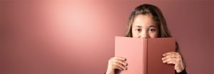 "Young girl peeking over pink book against soft LED-lit background, showcasing warm, even illumination for comfortable reading environments."