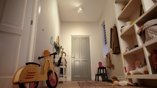 "Bright entryway with LED recessed lighting illuminating shelves, toys, and a children's balance bike."