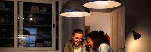 "Modern LED pendant lights create warm atmosphere for two women enjoying conversation, showcasing energy-efficient home lighting solutions."